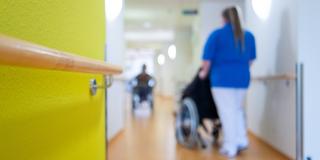 Eine Pflegerin schiebt einen Rollstuhl in einem Krankenhaus (Foto: dpa)