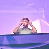 Calvin Harris steht auf der Bühne am DJ-Pult und setzt sich Kopfhörer auf. (Foto: picture alliance / Photoshot | -)