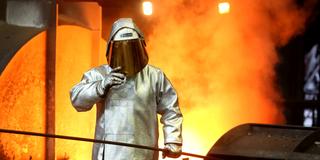 Ein Mitarbeiter prüft flüssiges Metall am Hochofen (Foto: dpa/Roland Weihrauch)