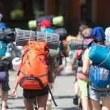 Jugendliche gehen mit ihren Rucksäcken und aufgeschnallten Schlafmatten durch die Innenstadt. (Foto: dpa)