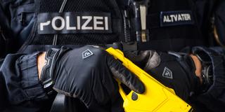Ein Polizist hält eine Elektroschockwaffe in der Hand. (Foto: picture alliance/Andreas Arnold/dpa)