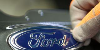 Eine Markenplakette von Ford wird an einem Fahrzeug angebracht (Foto: picture alliance/dpa | Oliver Berg)