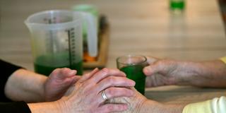 Betreuerin fasst die Hände einer Seniorin (Foto: picture alliance/dpa | Ina Fassbender)