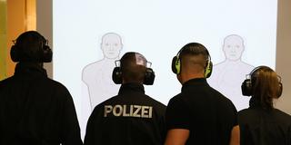 Polizisten stehen auf einem Schießstand vor einer Wand mit projizierten Zielen. (Foto: picture alliance/dpa | Karl-Josef Hildenbrand)