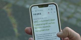 Eine Person hält ein Handy in der Hand und ruft die Homepage der Uniklinik Homburg auf (Foto: SR)