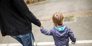 Ein Kind läuft an der Hand einer Begleitperson über eine Straße (Foto: picture alliance/dpa | Marcel Kusch)