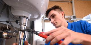 Auszubildender im Installateur- und Heizungsbauerhandwerk an einer Übungswand mit einer Rohrzange. (Foto: picture alliance/dpa/dpa-Zentralbild | Sebastian Kahner)