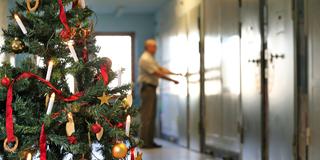 Auf einem mit einem Weihnachtsbaum geschmückten Gefängnisflur schließt ein Justizvollzugsbeamter eine Zellentür ab. (Foto: picture alliance/dpa/dpa-Zentralbild | Jan Woitas)