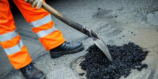 Ein Schlagloch wird notdürftig mit Asphalt ausgebessert (Foto: picture alliance / dpa | Uwe Zucchi)