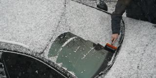 Ein Mann befreit die Windschutzscheibe seines Fahrzeugs vom Neuschnee. (Foto: picture alliance/dpa | Marcus Brandt)