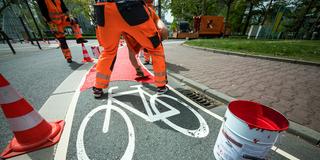 Arbeiter streichen rote Signalfarbe auf einem Radweg aus (Foto: picture alliance/dpa | Andreas Arnold)