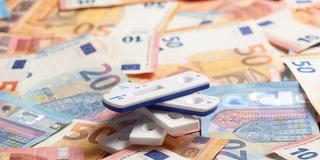 Coronatests liegen auf Euroscheinen (Foto: picture alliance / Westend61 | Mimafoto)