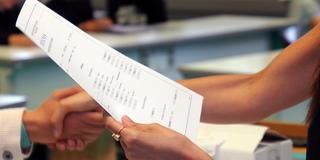 Ein Schulzeugnis wird mit Handschlag übergeben (Foto: picture alliance/dpa | Martin Wichmann)