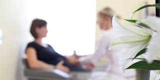 Schemenhaft sieht man eine Frau, die von einer Ärztin untersucht wird. (Foto: picture alliance / photothek | Ute Grabowsky)