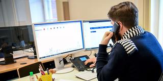 Mann sitzt vor Computer-Bildschirm und telefoniert. (Foto: picture alliance/dpa/dpa-Zentralbild | Britta Pedersen)