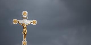 Ein Kruzifix ist vor dunklen Wolken zu sehen. (Foto: picture alliance/dpa | Marijan Murat)