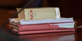 Gerichtsakten und ein Strafgesetzbuch liegen auf einem Tisch (Foto: picture alliance/dpa | Swen Pförtner)