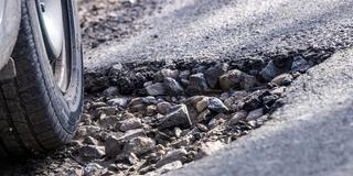 Ein Auto fährt durch ein Schlagloch. (Foto: picture alliance/dpa/dpa-Zentralbild | Jens Büttner)