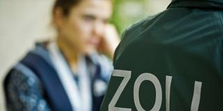 Symbolbild. Ein Zollbeamter kontolliert eine Mitarbeiterin eines Reinigungsbetriebes. (Foto: picture alliance / dpa | Nicolas Armer)