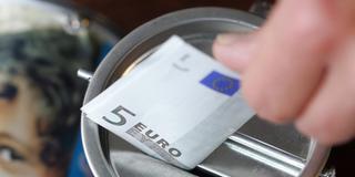 Eine Hand steckt einen Fünf-Euro-Schein in eine Spendendose (Foto: dpa/Bernd Thissen)