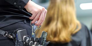 Eine Friseurin greift nach ihrer Schere in der Gürteltasche (Foto: picture alliance/dpa | Jan Woitas)