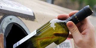 Jemand wirft eine leere Flasche in einen Altglascontainer (Foto: picture alliance / dpa | Tobias Hase)