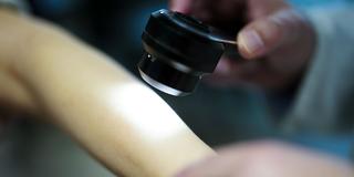 Ein Hautarzt untersucht bei einer Krebsvorsorgeuntersuchung eine Patientin mit einem Auflichtmikroskop (Foto: picture alliance/dpa/APA | Eva Manhart)