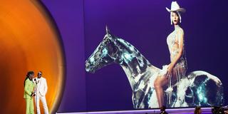 Zwei Männer stehen auf einer Bühne, im Hintergrund ist ein Bild von Sängerin Beyoncé auf einem Pferd zu sehen.  (Foto: picture alliance/dpa/Invision/AP | Chris Pizzello)