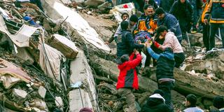 Menschen und Rettungskräfte bergen eine Person aus einem eingestürzten Gebäude nach schweren Erdbeben in der Türkei (Foto: picture alliance/dpa/IHA/AP | Elifaysenurbay)