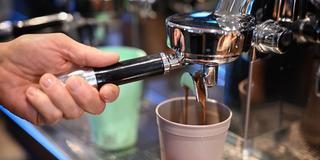 Ein Barista bereitet einen Kaffee zu, der in einen Mehrwegbecher fließt. (Foto: picture alliance/dpa | Felix Kästle)