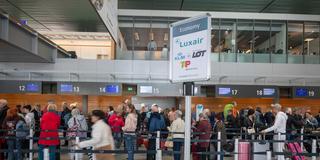 Passagiere stehen mit ihrem Gepäck an einem Abflugschalter des Luxemburger Flughafens Findel.  (Foto: picture alliance/dpa | Harald Tittel)