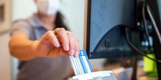 Eine Medizinische Fachangestellte schiebt in einer Hausarztpraxis die Versichertenkarte der Krankenkasse eines Patienten in das Lesegerät (Foto: picture alliance/dpa | David Inderlied)
