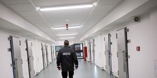 Ein Justizbeamter patrouilliert über einen Gefängnisflur (Foto: picture alliance/dpa | Christian Charisius)