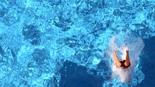 Ein Mensch landet nach einem Sprung in einem Schwimmbecken. (Foto: dpa)