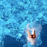 Ein Mensch landet nach einem Sprung in einem Schwimmbecken. (Foto: dpa)