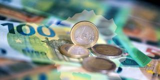 Geldscheine und Münzen liegen auf einem Tisch, darüber sind die Umrisse des Saarlandes gelegt (Foto: picture alliance/dpa | Monika Skolimowska)