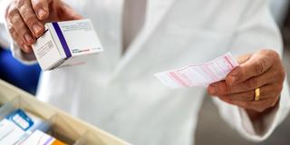 Ein Apotheker hält ein Medikament und ein Rezept in der Hand (Foto: picture alliance/dpa | Monika Skolimowska)