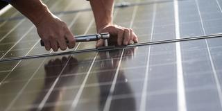 Ein Facharbeiter montiert Photovoltaikmodule auf dem Dach eines Wohnhauses. (Foto: picture alliance/dpa | Marijan Murat)