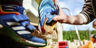 Auf einem Spielplatz wird Sand aus Kinderschuhen gekippt (Foto: picture alliance/dpa | Oliver Berg)