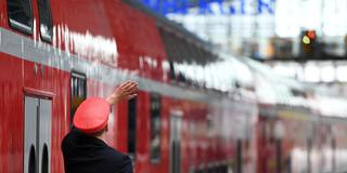 Ein Zugbegleiter steht neben einer Regionalbahn am Bahnsteig. (Foto: picture alliance/dpa | Soeren Stache)