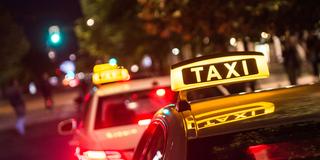 Taxischilder leuchten bei Nacht auf den Autodächern (Foto: picture alliance/dpa | Lino Mirgeler)