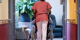 Eine Bewohnerin eines Pflegeheims wird von einer Pflegerin einen Gang entlang geschoben. (Foto: picture alliance/dpa | Marijan Murat)
