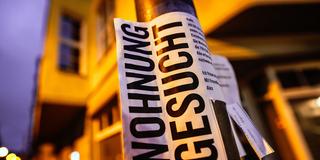 Ein Zettel mit der Aufschrift „Wohnung gesucht“ hängt an einem Laternenmast (Foto: picture alliance/dpa | Oliver Berg)
