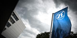 Eine Fahne mit dem Logo der ZF-Friedrichshafen AG weht unter bedrohlich wirkendem Wolkenhimmel (Foto: picture alliance/dpa | Felix Kästle)
