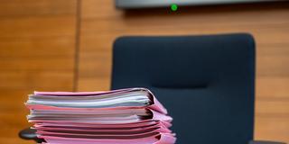 Symbolbild. Ein Aktenstapel liegt zu Protessbeginn auf dem Richtertisch im Verhandlungssaal. (Foto: picture alliance/dpa | Peter Kneffel)