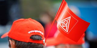 Menschen mit IG-Metall-Fahnen und -Mützen (Foto: picture alliance/dpa | Daniel Karmann)