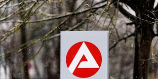 Das Logo der Agentur für Arbeit auf einer Stele bei winterlichem Wetter. (Foto: picture alliance / dpa | Matthias Balk)