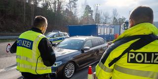Zwei Polizisten stoppen mit der Kelle ein heranfahrendes Auto. (Foto: picture alliance/dpa | Harald Tittel)