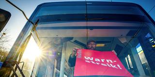 Ein Streik-Plakat der Gewerkschaft Verdi wird in die Frontscheibe eines Linienbusses gehängt (Foto: picture alliance/dpa | Jens Büttner)