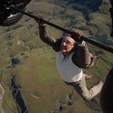 Ein Mann hängt an der Achso eines fliegenden Flugzeugs. (Foto: picture alliance / ZUMAPRESS.com | Paramount Pictures)